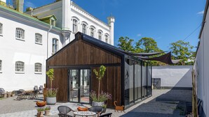 A courtyard with a modern building, traditional architecture, outdoor seating, and potted plants. - The White brig (Hudiksvall)
