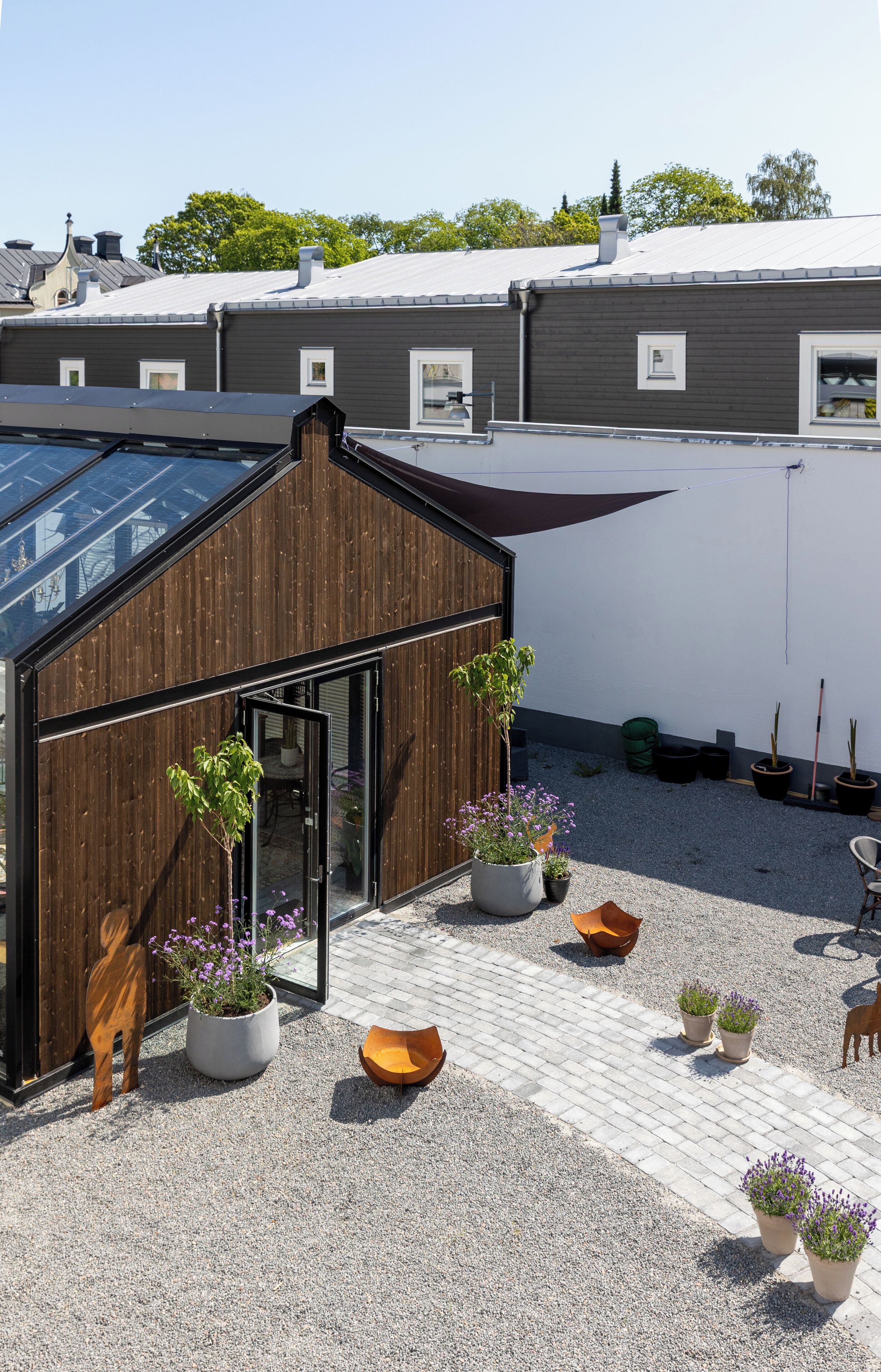 Un jardín en la azotea con plantas en macetas, una estructura de madera y un cielo despejado.