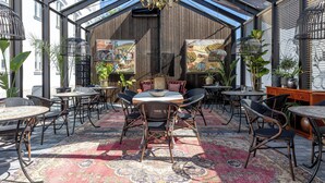 A conservatory with a dining area featuring round tables and chairs, a chandelier, and artwork on the walls. - The White brig (Hudiksvall)