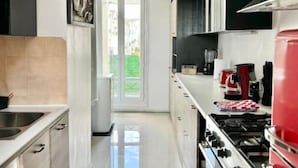 Una cocina moderna con un lavamanos de acero inoxidable, una estufa roja y una campana extractora negra.
