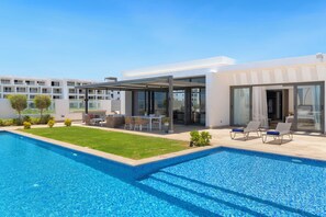 Et moderne hotel med swimmingpool, udendørs siddeområde og glasdøre til en overdækket terrasse.