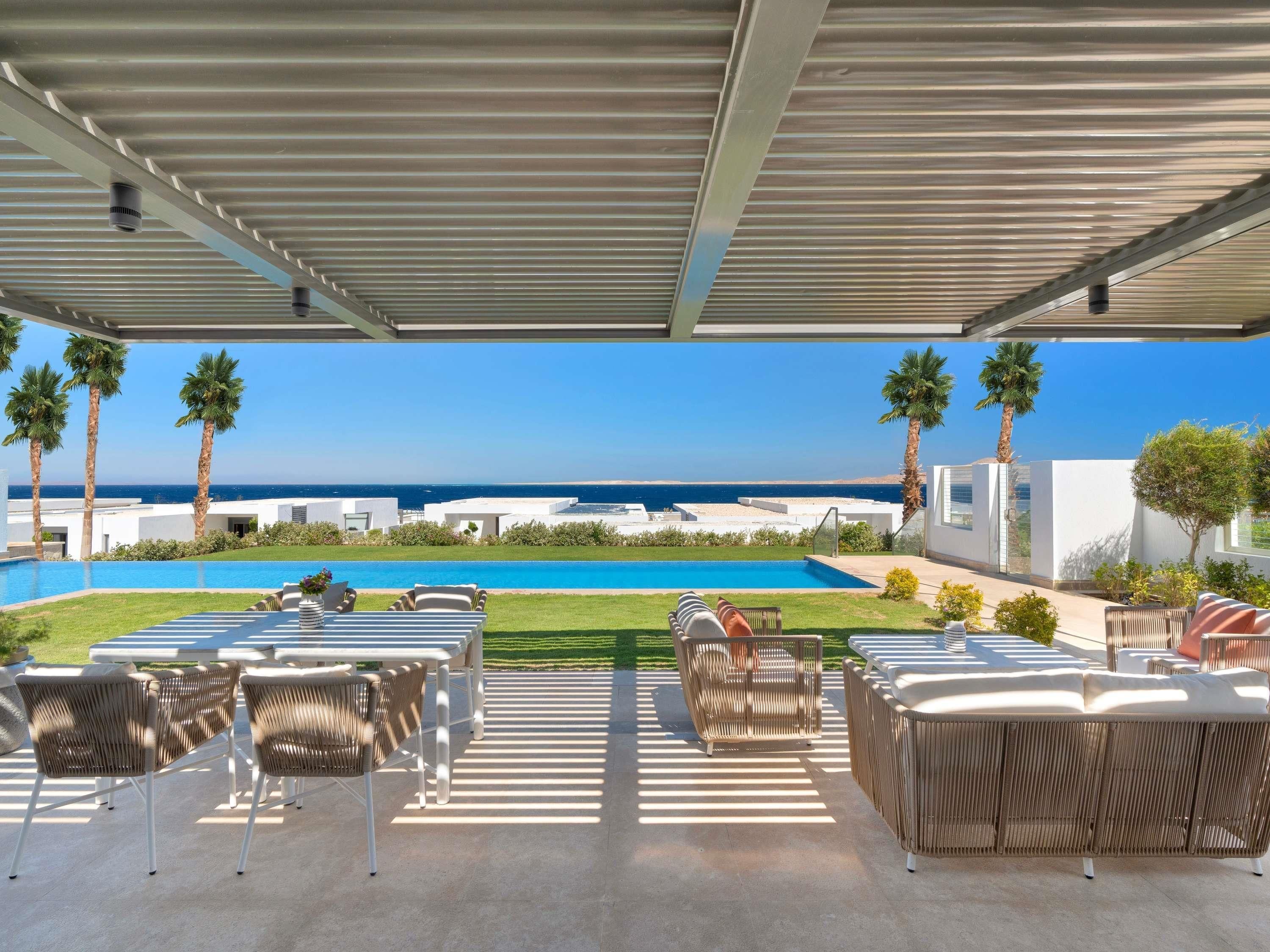 An outdoor seating area with a pool and a view of the sea.