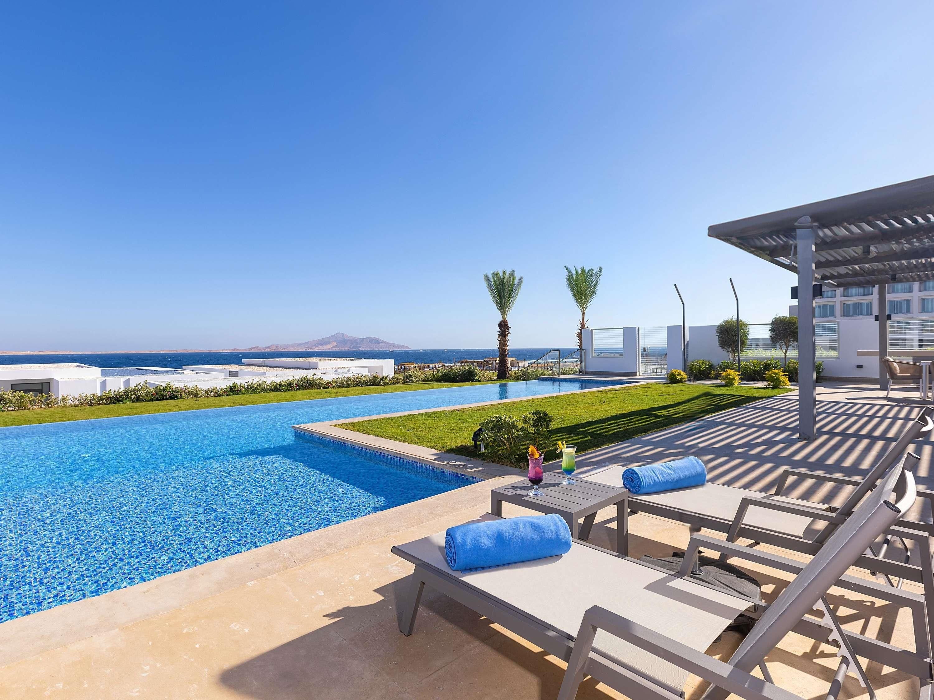 A poolside area with lounge chairs and a view of the sea.