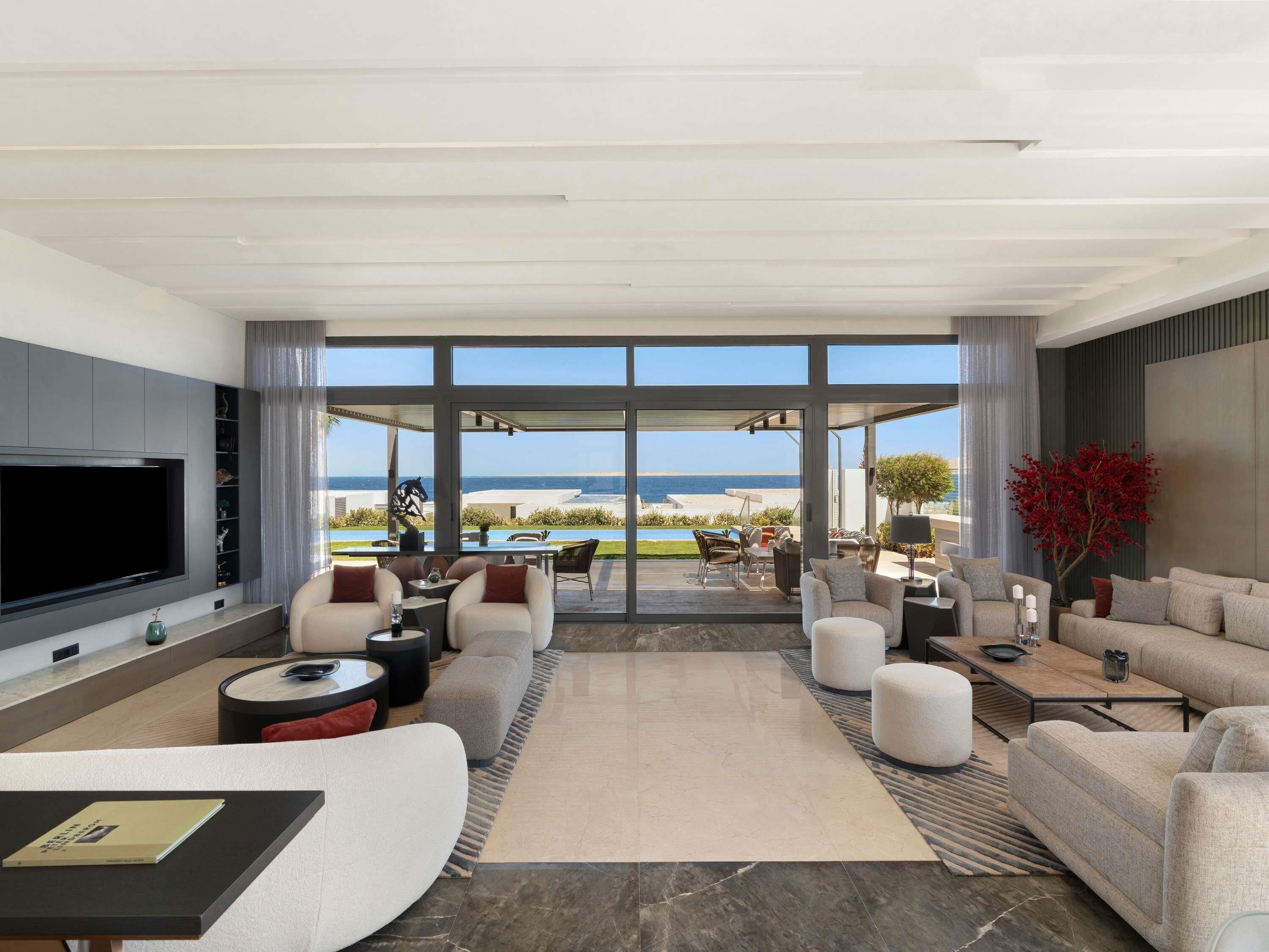 Una sala de estar moderna con un televisor grande, asientos cómodos y vista a la playa.