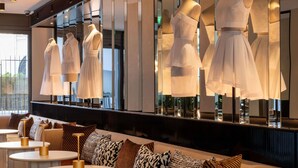 A modern hotel lobby with a seating area, a mirrored wall with dress displays, and a view of the outdoors. - Hotel Maison Hamelin Paris - Handwritten Collection (Paris)