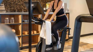 A woman on an exercise bike in a room with wooden shelves and a patterned floor. - Hotel Maison Hamelin Paris - Handwritten Collection (Paris)