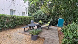 A patio area with picnic tables and chairs, surrounded by greenery and a building. - hotelF1 Montpellier Sud (Rénové) (Lattes)