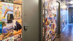 A hallway with a wall covered in vintage travel posters and a door with a keypad lock. - hotelF1 Montpellier Sud (Rénové) (Lattes)