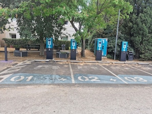 Un espace de stationnement équipé de quatre bornes de recharge pour véhicules électriques, chacune étant identifiée par un numéro.