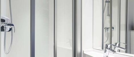 A modern bathroom with a glass shower enclosure, a white sink, and a large mirror.
