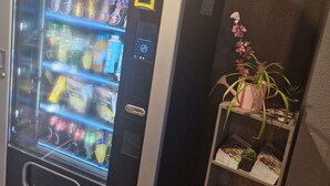 A vending machine with various snacks and drinks, a digital payment terminal, and a small potted plant on a shelf. - hotelF1 Montpellier Sud (Rénové) (Lattes)
