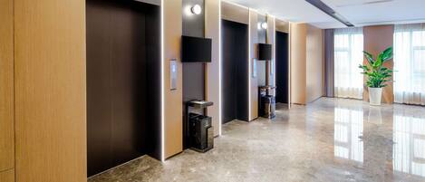 Un hall d’hôtel moderne avec un sol en marbre poli, des lambris en bois et une plante en pot.