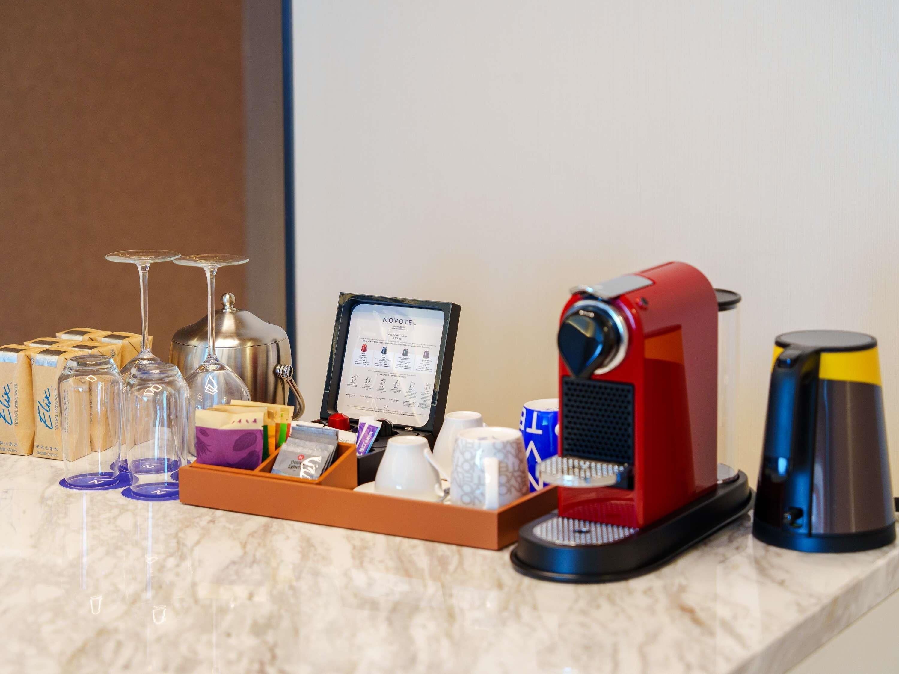 En minibar med en kaffemaskin, vinglas och olika typer av behållare för drycker.