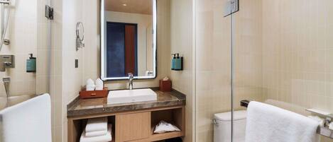 A modern bathroom with a large mirror, a sink, a toilet, and a shower.