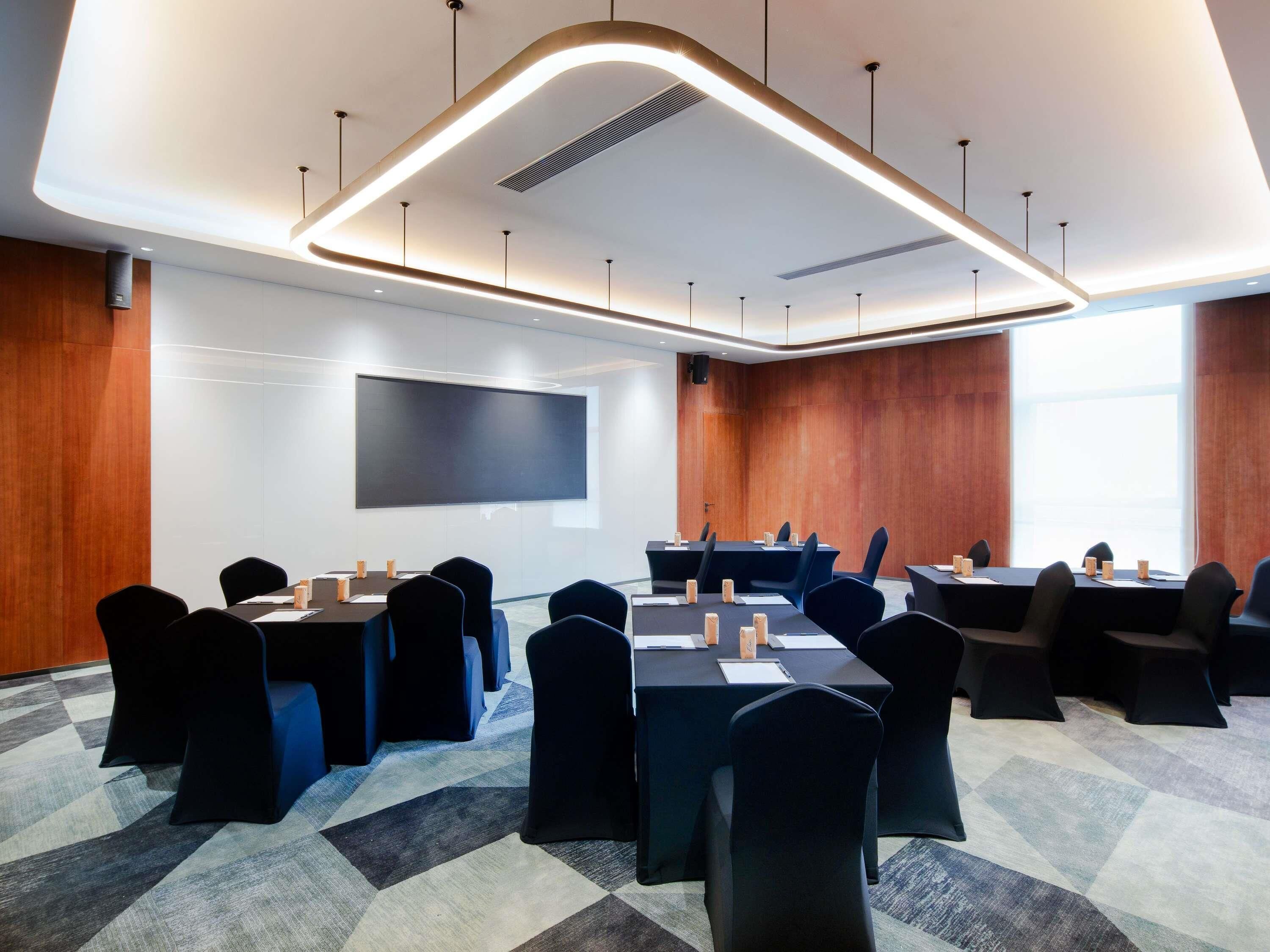 Une salle de conférence moderne équipée d’un grand écran, de plusieurs tables et de chaises.