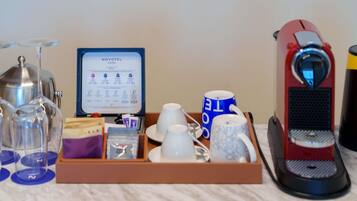 Preparación de un minibar de hotel con una cafetera, tazas para café y té, una bolsita de té, un vaso y una tabla con el menú.