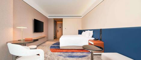 Una habitación de hotel con cama, escritorio, silla, televisor y una pequeña mesa.