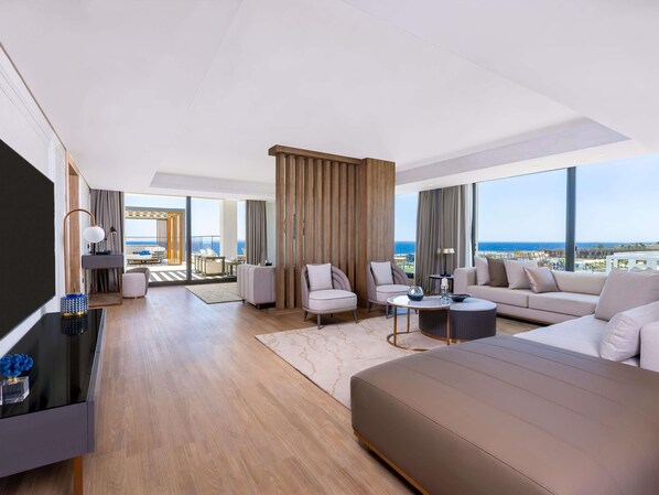 Una habitación de hotel moderna con una cama grande, un sofá, un televisor y un balcón con vista al mar.