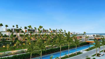 A resort with a pool, palm trees, and a view of the ocean.