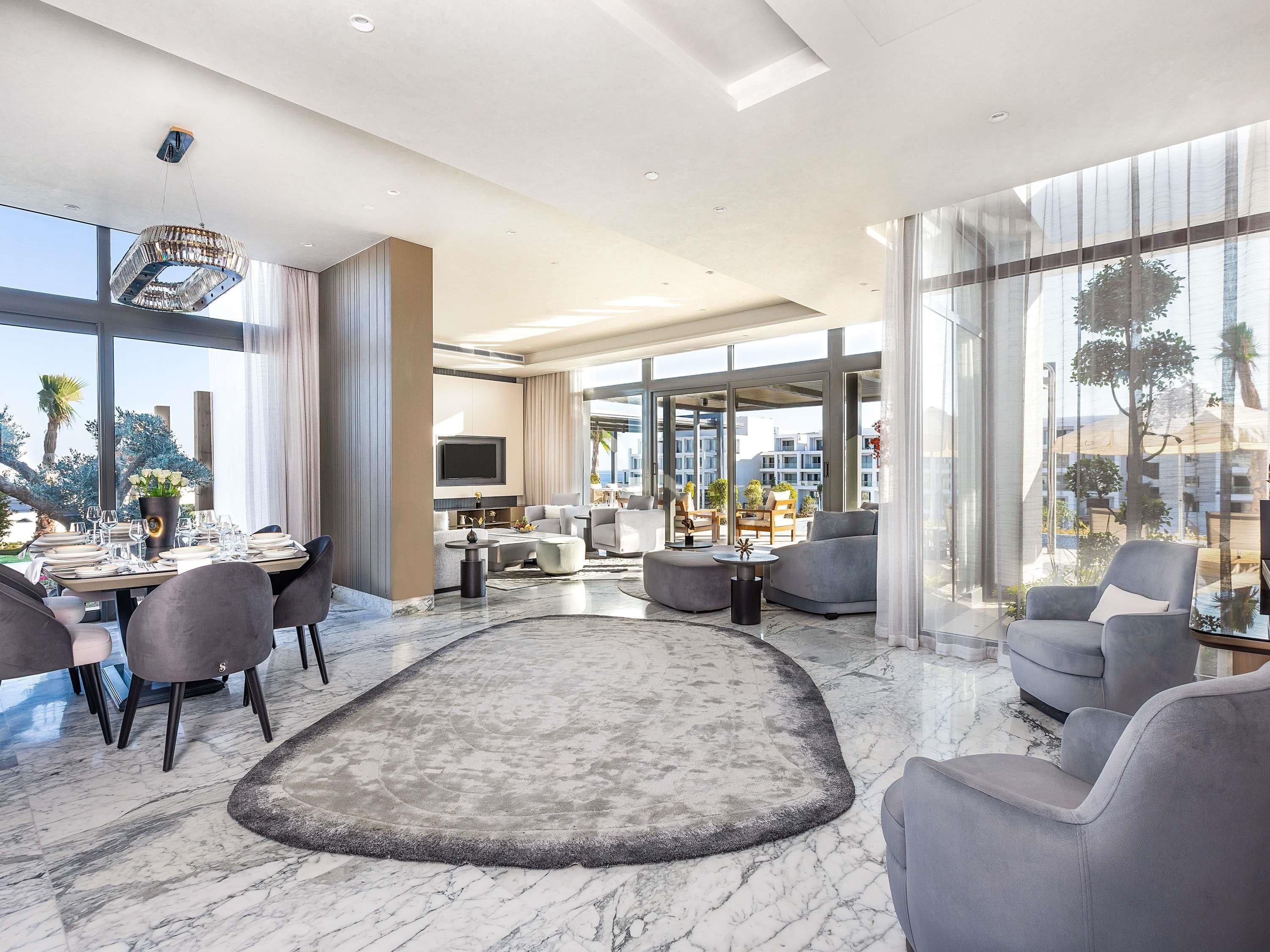 A modern living room with a dining area, large windows, and a view of the city.