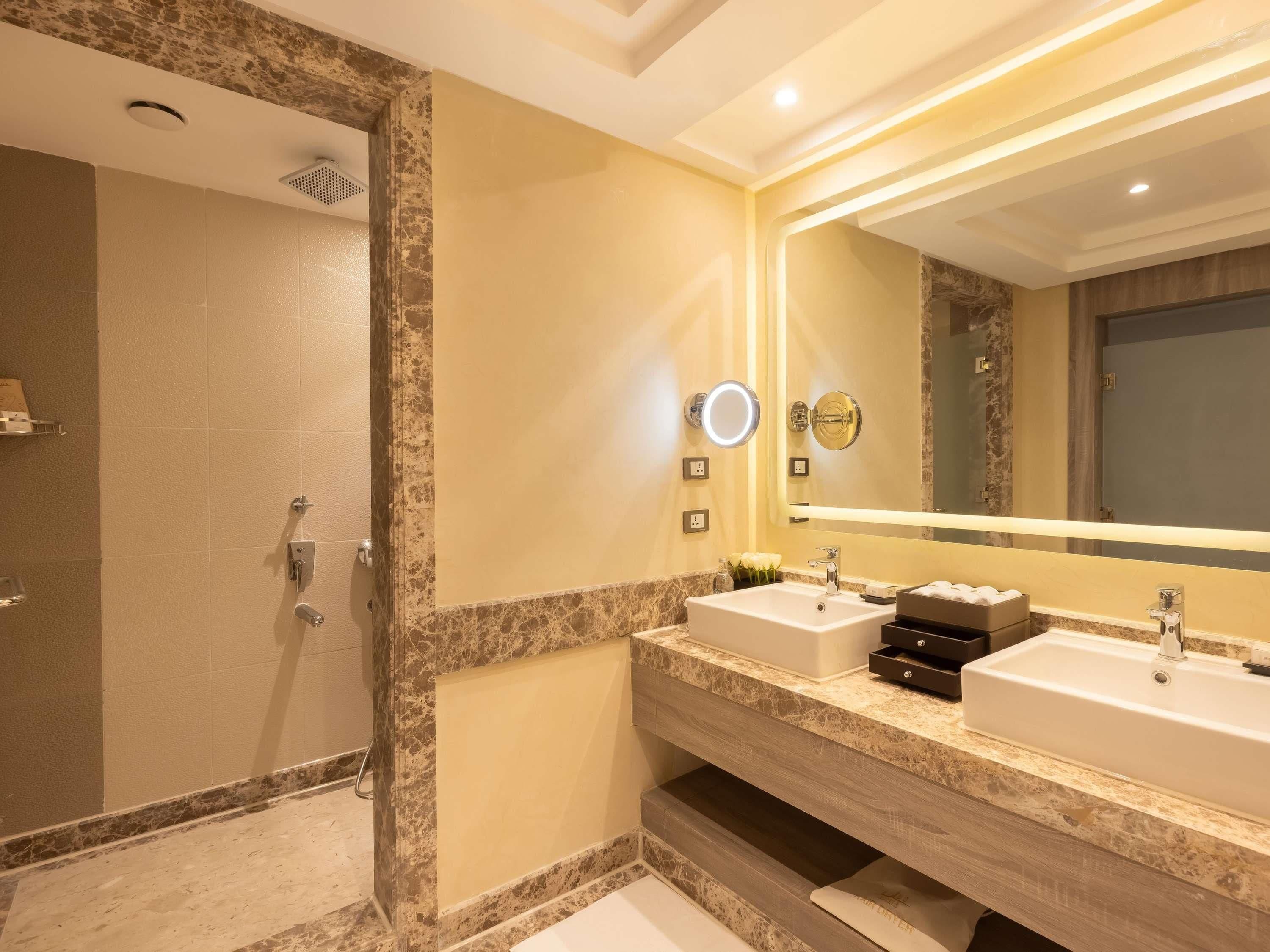 A modern bathroom with two sinks, a large mirror, and a shower area.