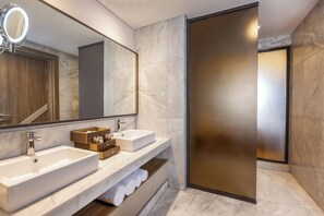 A modern bathroom with two sinks, a large mirror, and a towel rack.