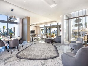 Una sala moderna con comedor, ventanas amplias y vista a la ciudad.
