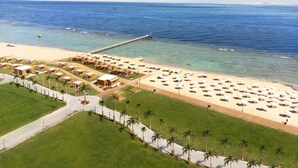 A beach resort with a sandy beach, palm trees, and a pier extending into the sea. - Rixos Radamis Sharm El Sheikh (Sharm El Sheikh)