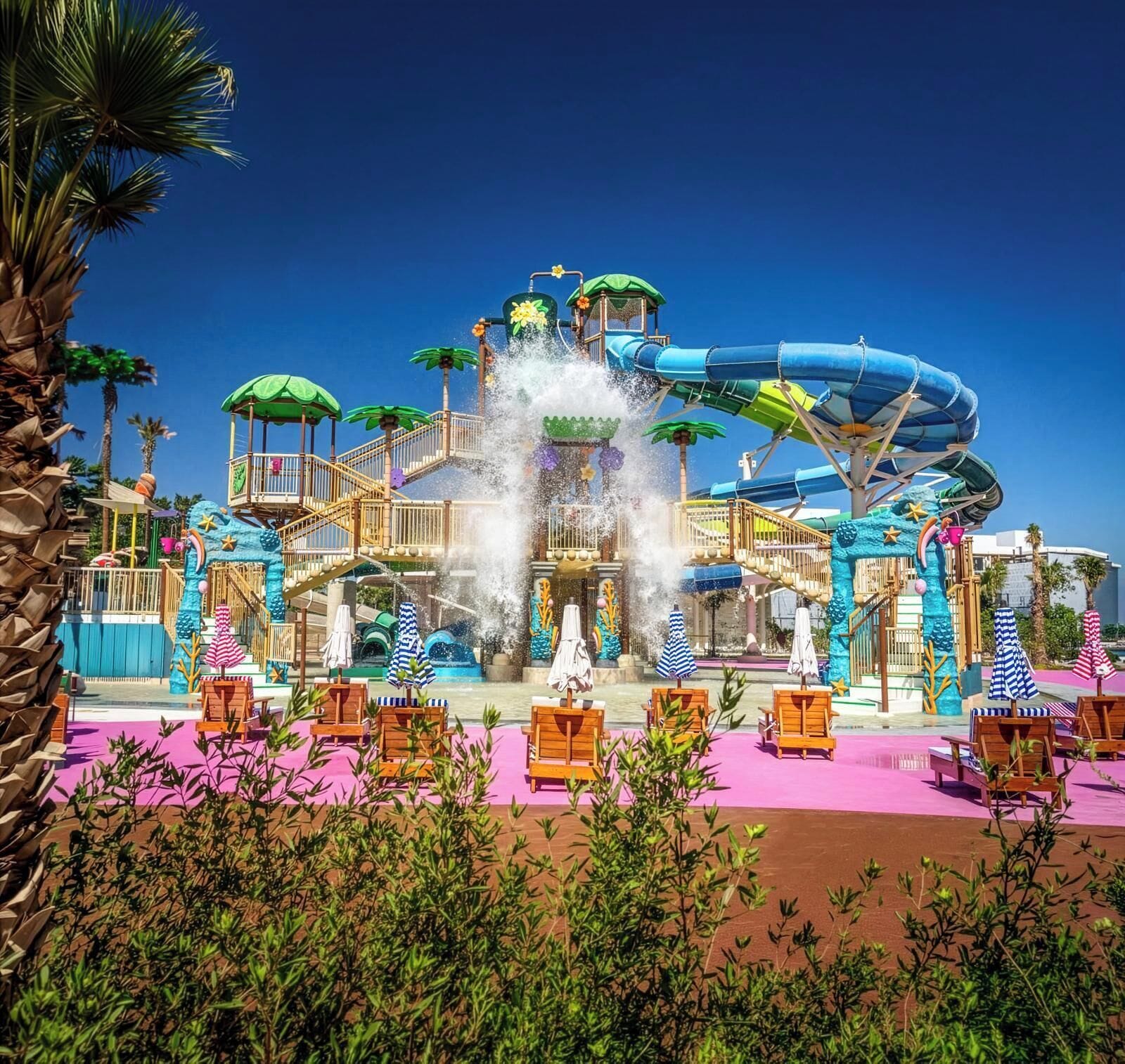 Ein Wasserpark mit einer großen Rutsche, mehreren Ebenen und einem Poolbereich mit Liegestühlen.