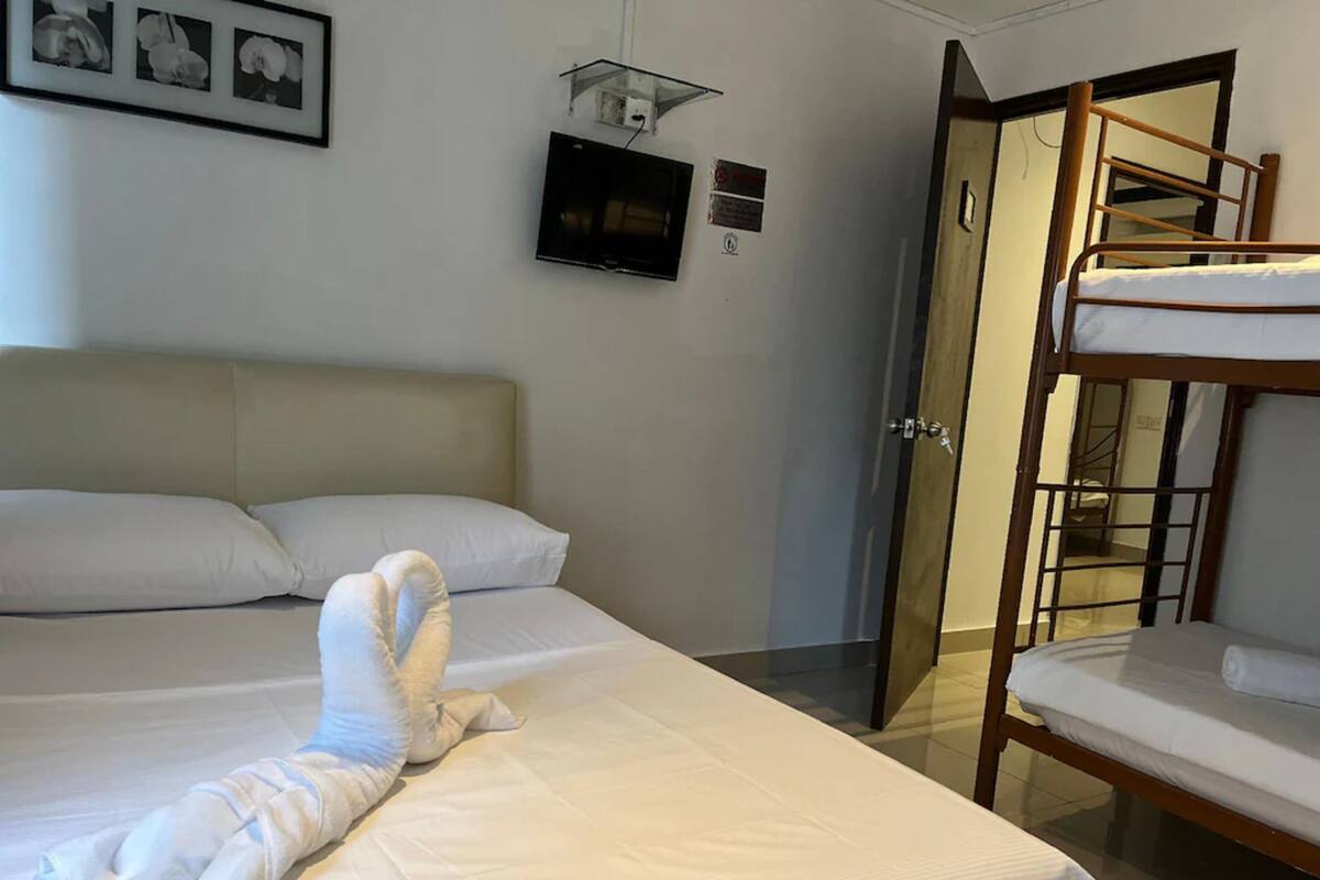 Een hotelkamer met een bed, een televisie, een deur en een stapelbed.