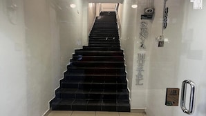 A staircase leading to a room labeled "SANTA HOTEL" with a handrail on the right and a sign indicating a shower area on the left. - Hotel O Senja Hostel Chinatown (Kuala Lumpur)