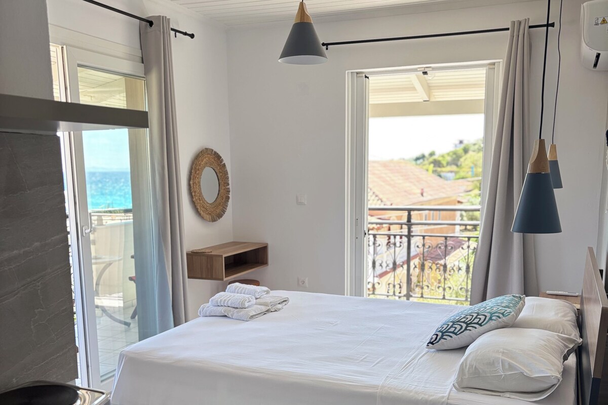 A hotel room with a bed, a TV, a desk, and a balcony with a view.