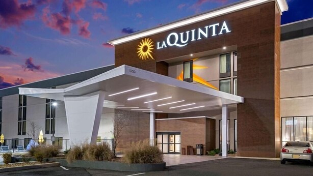 A modern hotel with a prominent 'La Quinta' sign, featuring a sun logo. - La Quinta Inn And Suites By Wyndham Columbus Ms (Columbus)