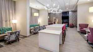 A modern hotel lobby with a reception desk, seating area, and a chandelier. - La Quinta Inn And Suites By Wyndham Columbus Ms (Columbus)