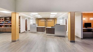 A spacious lobby with a light wood floor, a reception desk, and a seating area with a television. - La Quinta Inn And Suites By Wyndham Columbus Ms (Columbus)