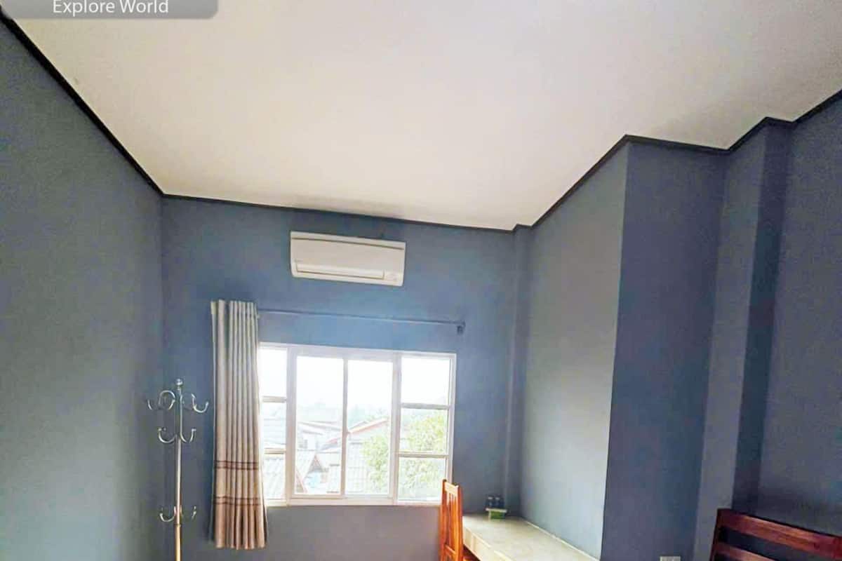 A bedroom with two beds, a desk, and a window.