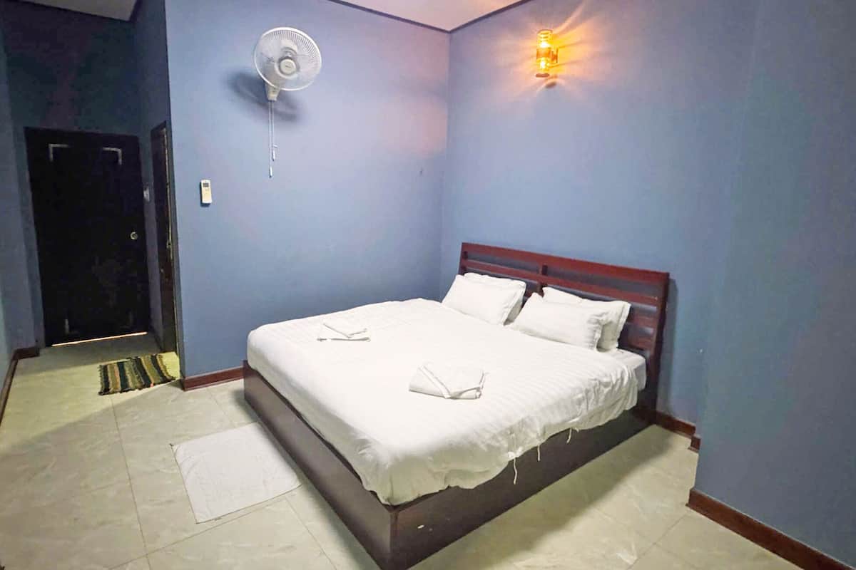 A bedroom with a bed, a wall-mounted fan, and a nightlight.