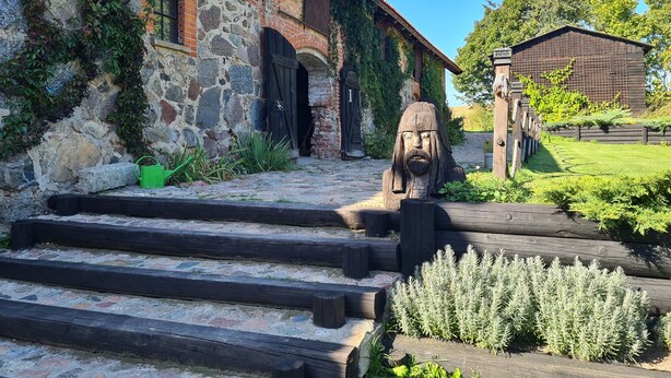 Un rústico edificio de piedra con una escalera de madera que conduce a una puerta de madera.