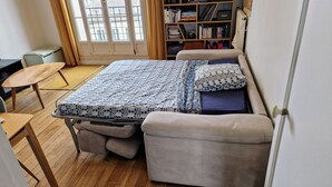 A compact room with a bed, a small desk, and a bookshelf. - Appartement Familial Proche de la Gare de Clamart (Clamart)