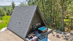 Een driehoekige hut met een jacuzzi, buiten zitplaatsen en een vuurkuil.