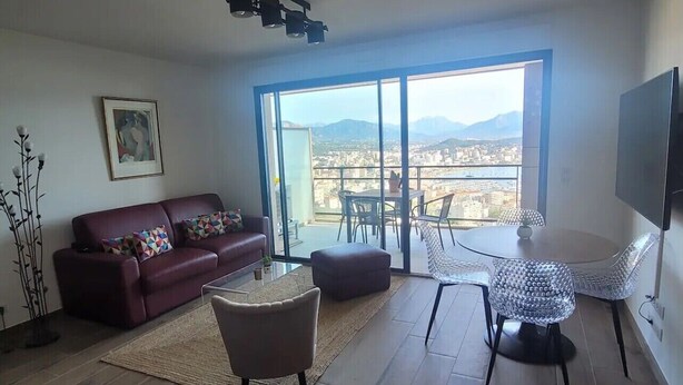 Un ampio soggiorno con una grande finestra, un divano, un tavolino da caffè e una TV.