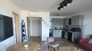 Un soggiorno moderno con angolo ristoro, cucina e un divano rosso.