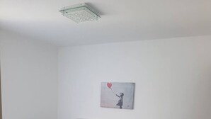 Un letto rifatto con un copriletto bianco e blu, due cuscini e un comodino con una lampada.