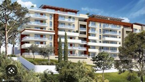 Un edificio residenziale a più piani con balconi, tetto piano e un'area giardino curata.