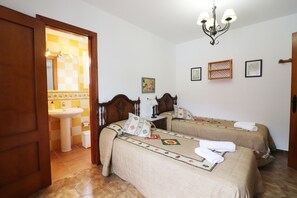 A hotel room with two beds, a bathroom with a sink, and a chandelier.