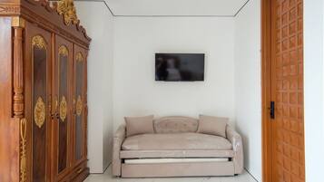 A room with a sofa, a television mounted on the wall, and a wooden cabinet.