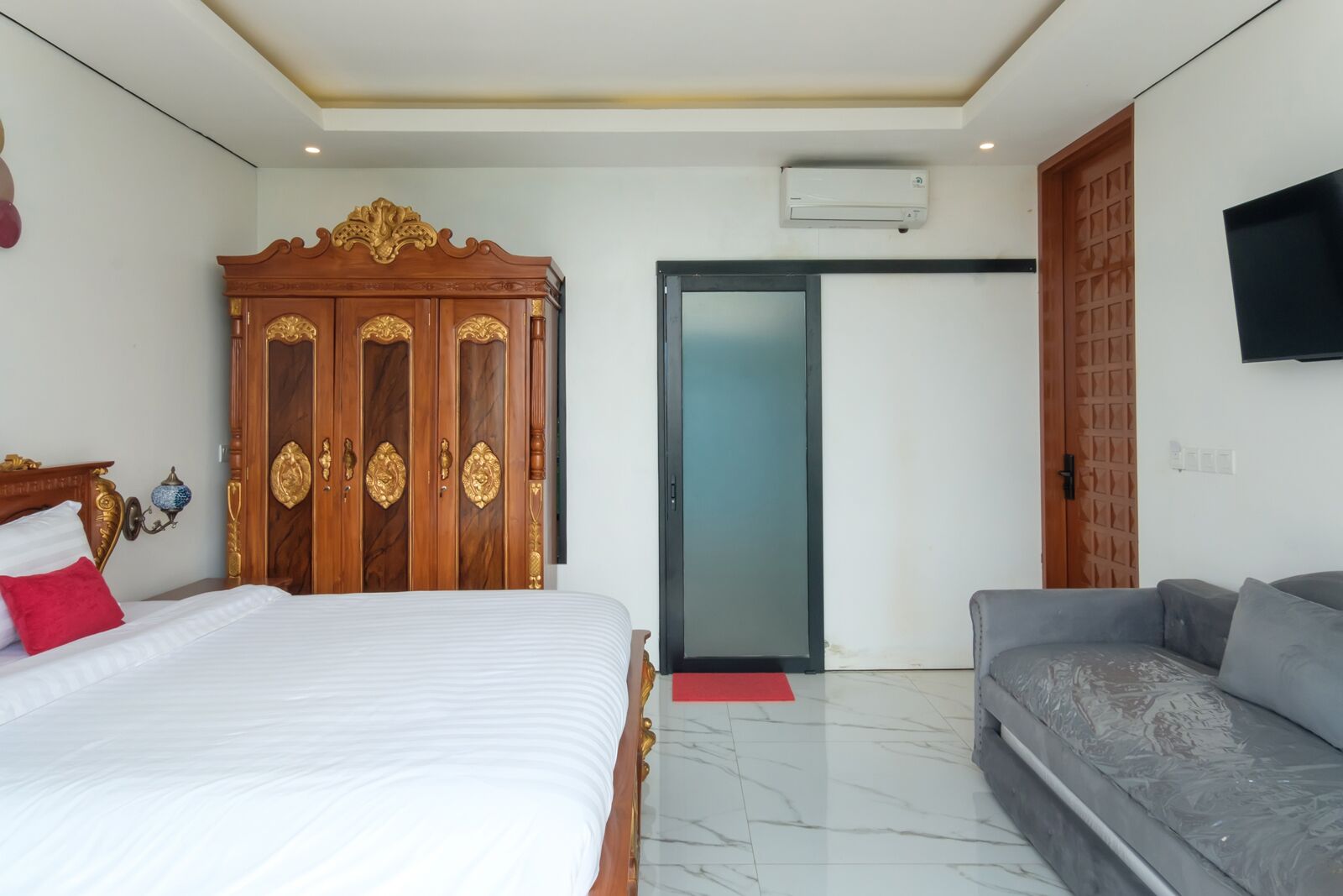 A bedroom with a bed, a wardrobe, a sofa, a TV, and a sliding door.
