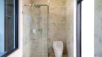 A modern bathroom with a glass-enclosed shower, a toilet, and a marble-tiled wall.