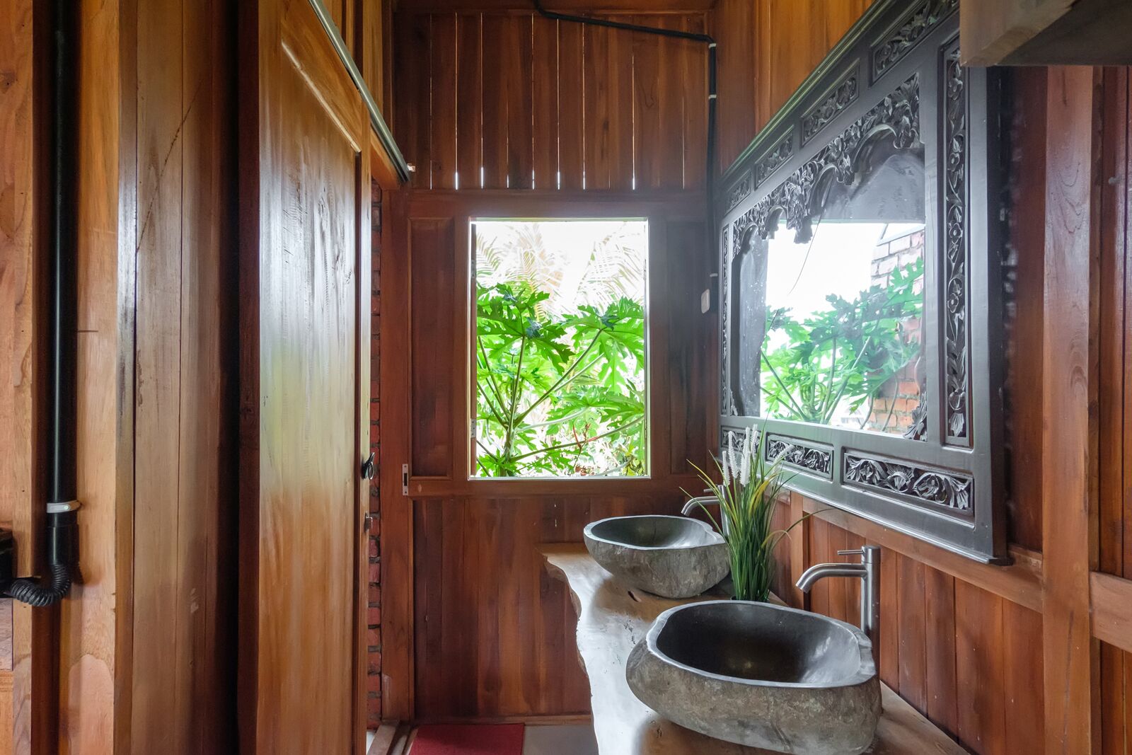 Une salle de bain en bois avec deux vasques en pierre et une fenêtre donnant sur un paysage verdoyant.