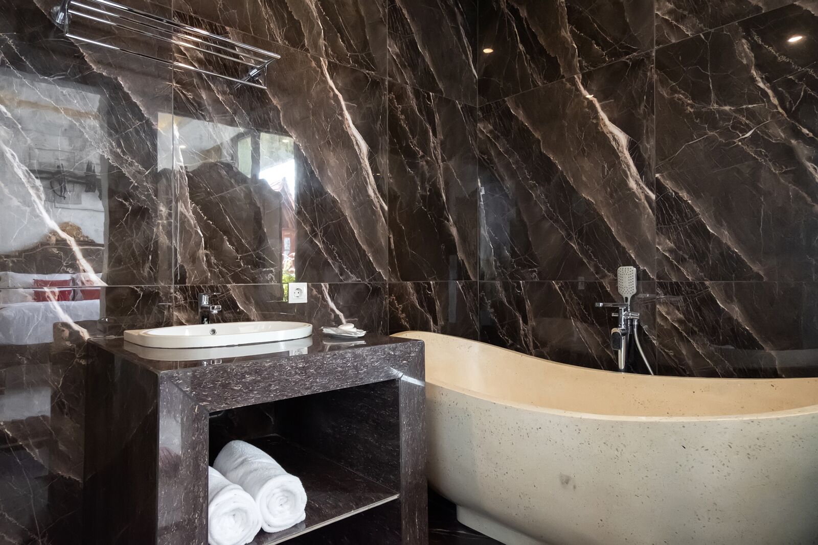 A modern bathroom with a marble vanity, a sink, and a freestanding bathtub.